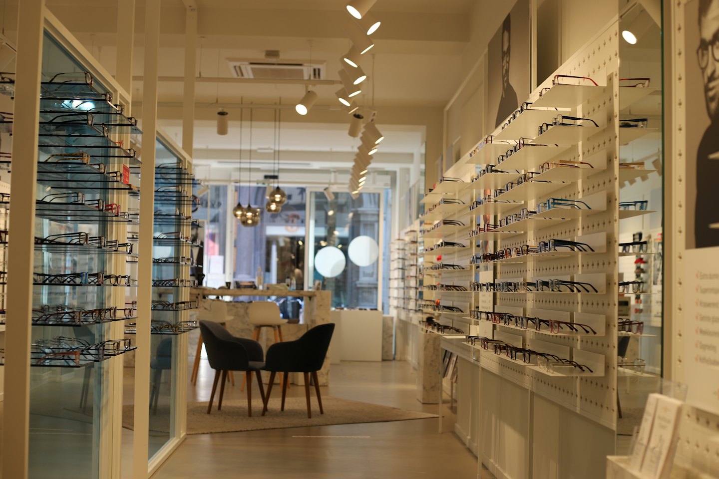 Moderno negozio di ottica con occhiali esposti su scaffali e sedie.